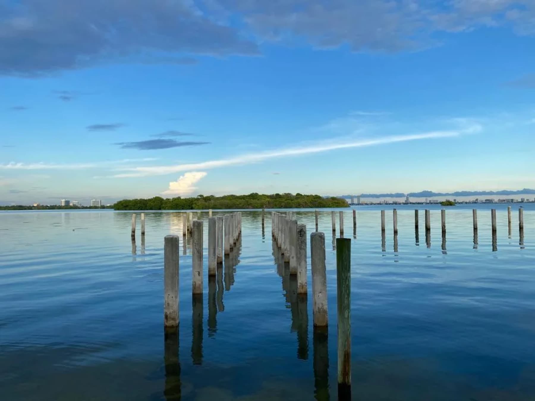 Calm bay water and mangrove island beyond the pilings